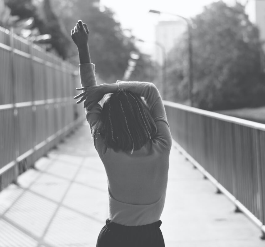 woman walking down street from the back and stretching