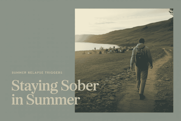 Person walking on a trail near a lake during summer for sobriety support.